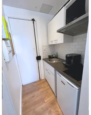 a small kitchen with a white refrigerator and a sink at Cosy studio ensoleillé - centre-ville – TRAM/AC in Nice