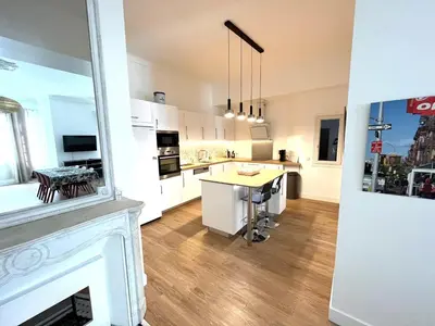 a kitchen with white cabinets and a fireplace at Large Haussmanian appartment in the heart of Nice in Nice