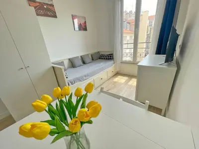 a vase of yellow flowers on a table in a room at Studio au coeur de Nice in Nice