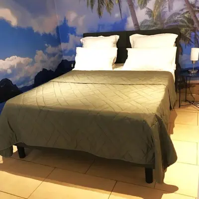 a bed with a green comforter and white pillows at Summer Beach Studio, 4 persons, mobile AC, Old Town in Nice