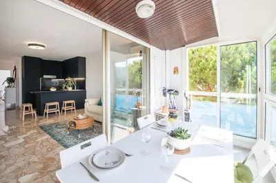 a kitchen and living room with white furniture and large windows at Résidence méditerranée - Beachfront - Sun and Seaview - Pool - Private Parking in Cagnes-sur-Mer