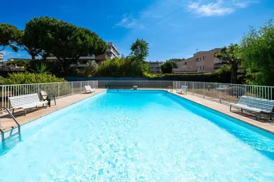a large swimming pool with two chairs and a fence at Résidence méditerranée - Beachfront - Sun and Seaview - Pool - Private Parking in Cagnes-sur-Mer