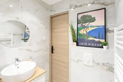 a bathroom with a sink and a door with a tree painting at #10 2Pièces Fricéro 3min to the beach/Balcon & AC in Nice