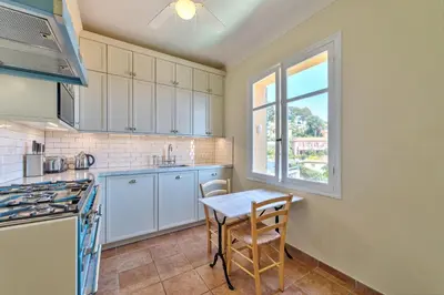 a kitchen with white cabinets and a table and a window at Villa Francesca Beautiful villa with sea view and swimming pool! in Villefranche-sur-Mer
