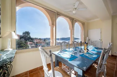 a dining room with a table and some windows at Villa Francesca Beautiful villa with sea view and swimming pool! in Villefranche-sur-Mer