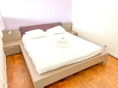 a bedroom with a bed with white sheets and a wooden floor at Horizon in Saint-Laurent-du-Var