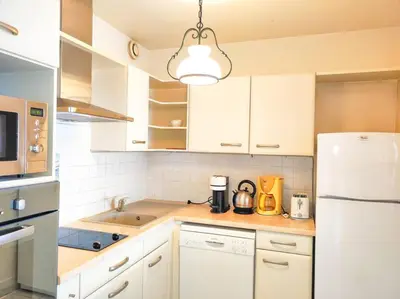 a kitchen with white cabinets and a white refrigerator at Horizon in Saint-Laurent-du-Var