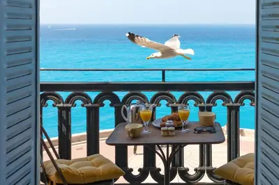 a bird flying over a table on a balcony with the ocean at L50 2P Rauba Capeu SEA View IloveNice Balcony&AC in Nice