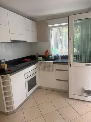 a kitchen with white cabinets and a window and a door at Studio proche mer avec piscine Cros de cagnes in Cagnes-sur-Mer