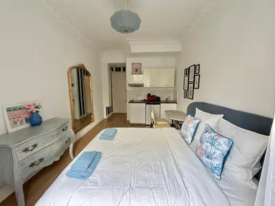 a bedroom with a white bed and a kitchen at Studio 2 steps from the sea near the Negresco hotel in Nice