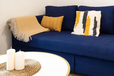 a blue couch with pillows and a table at #44 1 BDR Flat Cap AC balcony 5mins walk to beach in Nice