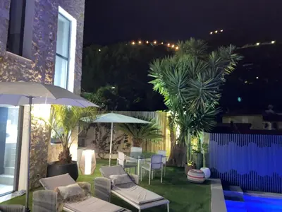 a patio with chairs and umbrellas at night at Luxury Villa with Pool & Sea View-10 Minutes from Monaco in Èze