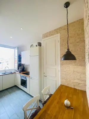a kitchen with a wooden table and aendant light at Promenade des Anglais /Carré d'or - 2 mins plages in Nice