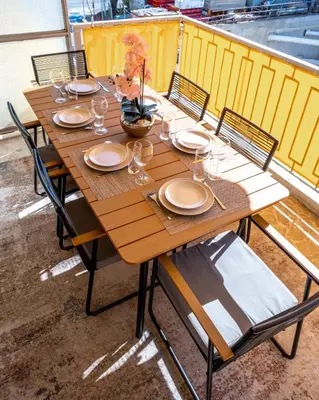 a wooden table with chairs and plates and glasses at 3 pièces au cœur du cros de cagnes in Cagnes-sur-Mer