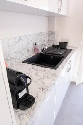a kitchen counter with a black sink in a white kitchen at 3 pièces au cœur du cros de cagnes in Cagnes-sur-Mer