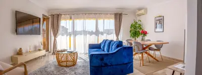 a living room with a blue couch and a table at 3 pièces au cœur du cros de cagnes in Cagnes-sur-Mer
