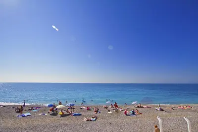 a group of people on a beach near the ocean at Luxury sea front suite Promenade in Nice
