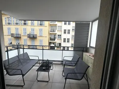 a balcony with chairs and a table and a view of a building at Superbe Appartement terrasse 2P à 5 min à pied du vieux Nice, du port et du Tram in Nice