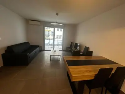 a living room with a black couch and a table at Superbe Appartement terrasse 2P à 5 min à pied du vieux Nice, du port et du Tram in Nice
