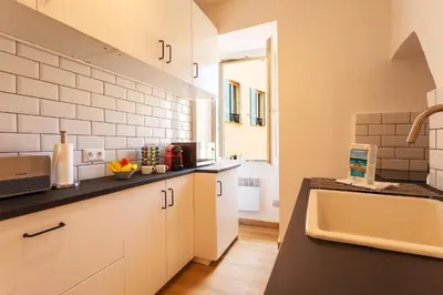 a kitchen with white cabinets and a sink at THE BAY AP4371 By Riviera Holiday Homes in Villefranche-sur-Mer