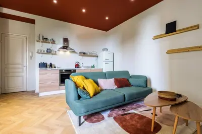 a living room with a blue couch and a kitchen at Charmant 3 pièces vue mer in Villefranche-sur-Mer
