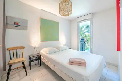 a bedroom with a bed and a chair and a window at Rez de jardin à 500 m de la plage in Cagnes-sur-Mer