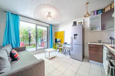 a kitchen and living room with a couch and a refrigerator at Rez de jardin à 500 m de la plage in Cagnes-sur-Mer