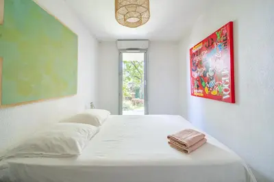 a white bed in a room with a window at Rez de jardin à 500 m de la plage in Cagnes-sur-Mer
