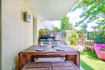 a wooden table with plates on it on a patio at Rez de jardin à 500 m de la plage in Cagnes-sur-Mer