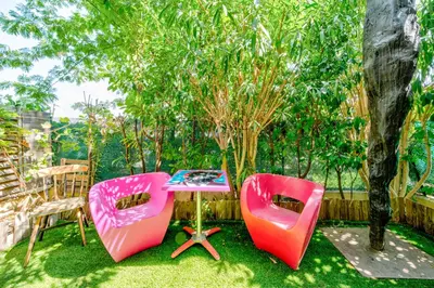 two pink chairs and a table in a yard at Rez de jardin à 500 m de la plage in Cagnes-sur-Mer