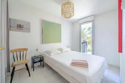 a bedroom with a bed and a chair and a window at Rez de jardin à 500 m de la plage in Cagnes-sur-Mer