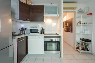 a kitchen with white appliances and brown cabinets at Rez de jardin à 500 m de la plage in Cagnes-sur-Mer