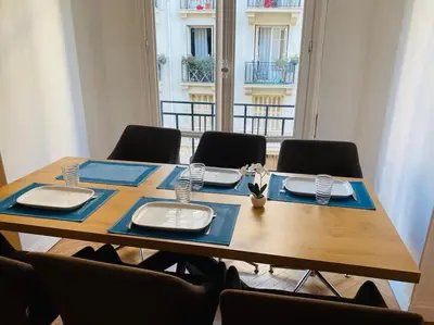 a wooden table with chairs and a table with dishes on it at Coeur de Nice emplacement idéal in Nice