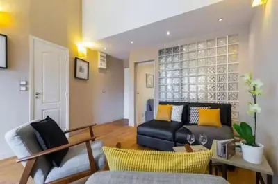 a living room with a black leather couch and yellow pillows at Signature Penthouse at Villefranche, Steps to Beach, Limited-Time Offer in Villefranche-sur-Mer