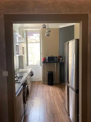 a kitchen with a stainless steel refrigerator and wooden floors at 3 P 75 M2 Centre de nice in Nice