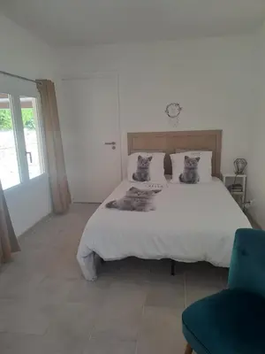 a bedroom with a large white bed and a blue chair at Maison du bonheur calme et verdure in Nice