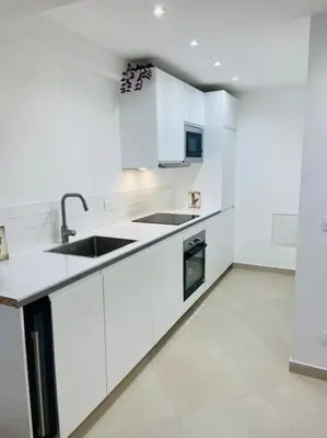 a white kitchen with white cabinets and a sink at T3 duplex cosy & calme au port - Tram in Nice