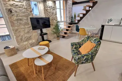 a living room with a tv and chairs and a table at T3 duplex cosy & calme au port - Tram in Nice