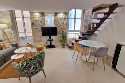 a living room with a couch and a table and chairs at T3 duplex cosy & calme au port - Tram in Nice