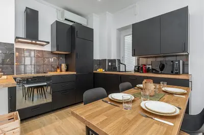 a kitchen with a wooden table and black cabinets at Confort Downtown 2 Bdr in Nice