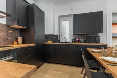 a kitchen with black cabinets and a wooden table at Confort Downtown 2 Bdr in Nice