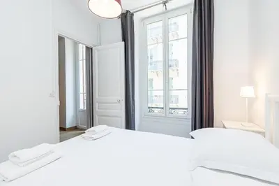 a white bedroom with two beds and a large mirror at Confort Downtown 2 Bdr in Nice