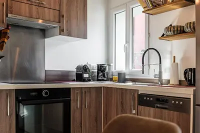 a kitchen with wooden cabinets and a sink and a stove at Cocon dans la vieille ville in Villefranche-sur-Mer