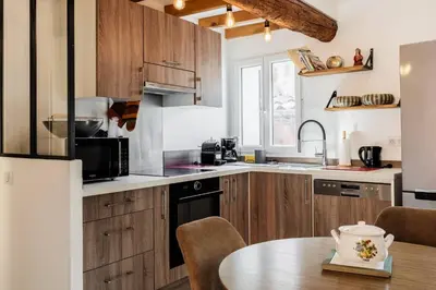 a kitchen with wooden cabinets and a wooden table at Cocon dans la vieille ville in Villefranche-sur-Mer