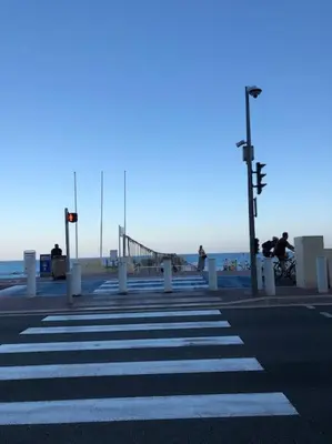 a crosswalk on a street with a beach and a pier at Vue mer, 2 pièces lumineux in Nice
