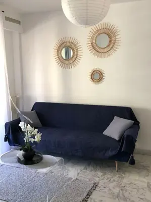 a living room with a blue couch and two mirrors at Vue mer, 2 pièces lumineux in Nice