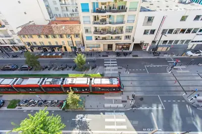 a red train traveling through a city with buildings at L28 Suite Californie 1min walk sea 3BDR/ AC & balcony in Nice