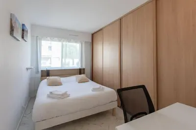 a bedroom with a bed and a chair and a window at L28 Suite Californie 1min walk sea 3BDR/ AC & balcony in Nice
