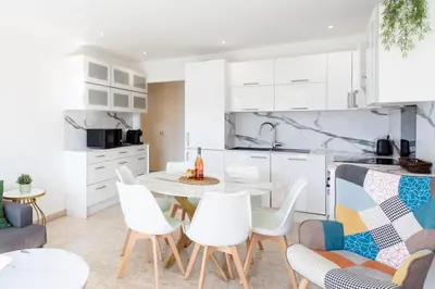 a kitchen with white cabinets and a table and chairs at L28 Suite Californie 1min walk sea 3BDR/ AC & balcony in Nice