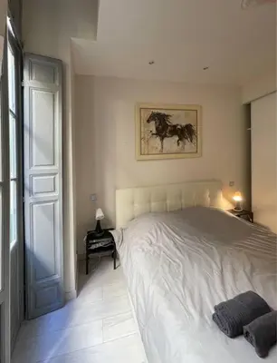 a bedroom with a white bed with a painting on the wall at Luxury apartment In the heart of old town Nice. in Nice